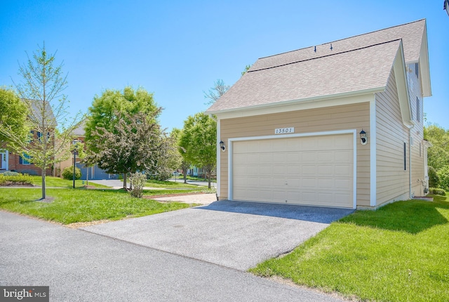view of side of property with a garage, a yard, and roof with shingles