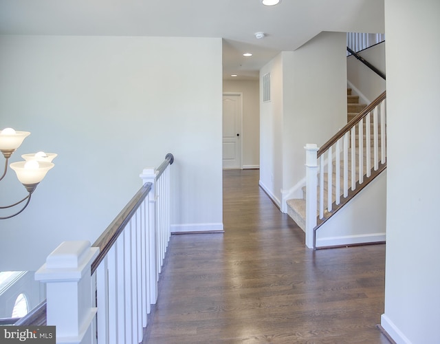 hallway featuring visible vents, wood finished floors, baseboards, recessed lighting, and an upstairs landing