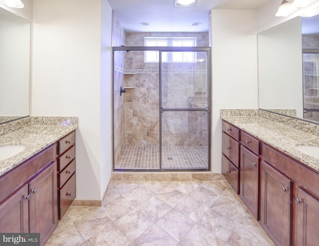 bathroom featuring a sink, baseboards, a stall shower, and two vanities