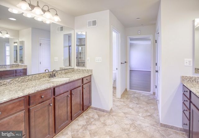 bathroom with visible vents, a sink, baseboards, and two vanities