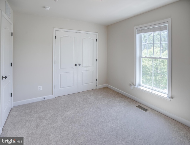 unfurnished bedroom featuring visible vents, carpet flooring, a closet, and multiple windows