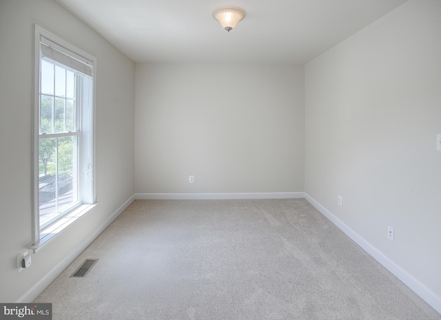 spare room featuring visible vents, baseboards, and light carpet