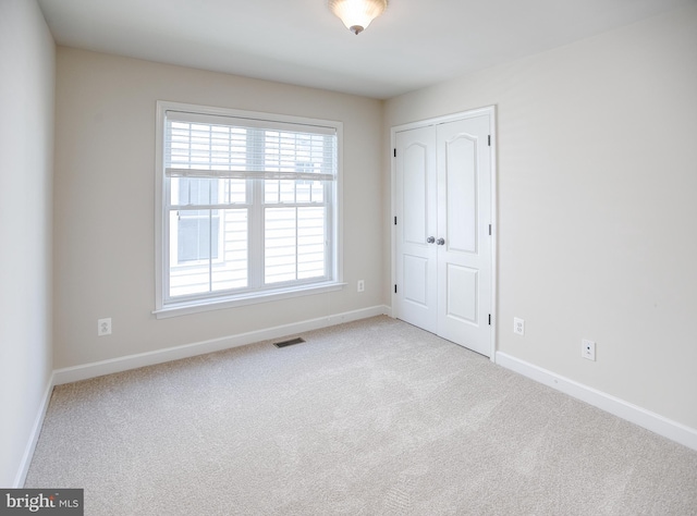 carpeted empty room featuring baseboards and visible vents