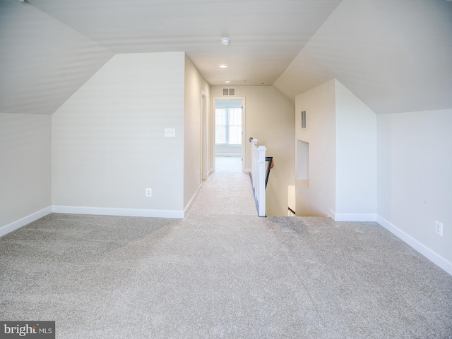 additional living space with carpet floors, baseboards, vaulted ceiling, and visible vents