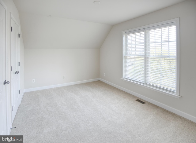 additional living space with carpet floors, baseboards, vaulted ceiling, and visible vents