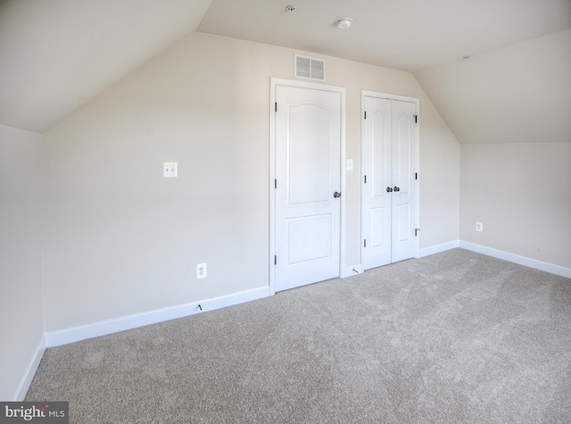 additional living space with carpet floors, baseboards, lofted ceiling, and visible vents