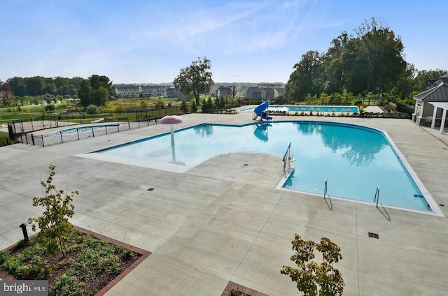 community pool with fence and a patio area