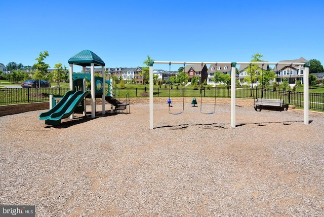 communal playground featuring fence and a residential view