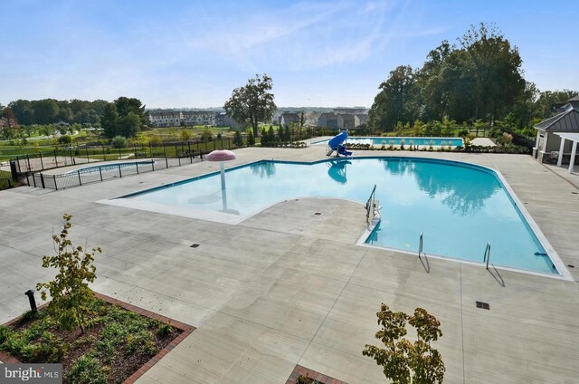 community pool with fence and a patio
