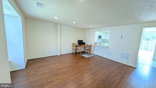 interior space featuring visible vents, recessed lighting, a textured ceiling, and dark wood-type flooring
