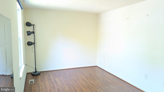spare room with baseboards, wood finished floors, and visible vents