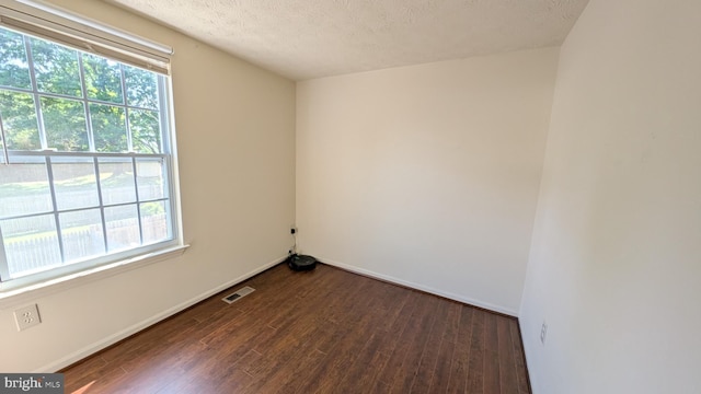 empty room featuring dark wood-style flooring and a wealth of natural light