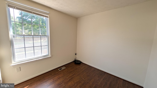 spare room with baseboards, dark wood-style floors, and a textured ceiling