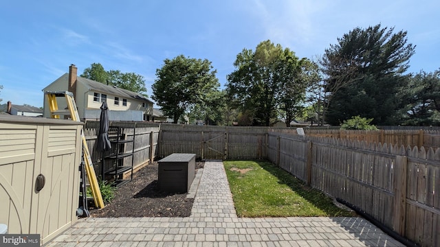 view of yard featuring a storage shed, an outdoor structure, a fenced backyard, and a patio area