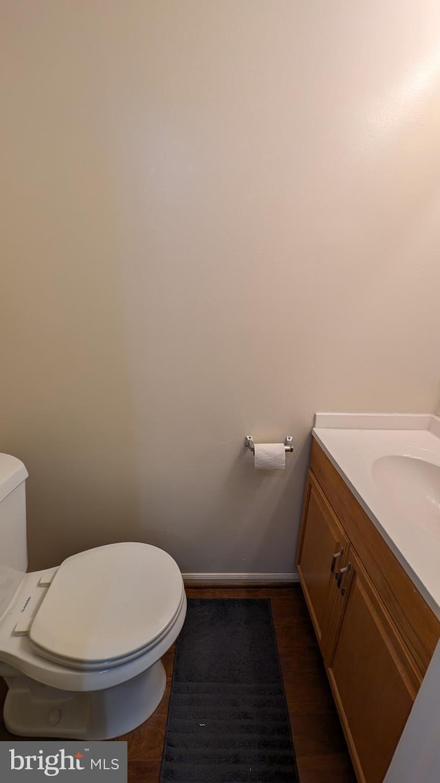 bathroom with vanity, baseboards, wood finished floors, and toilet