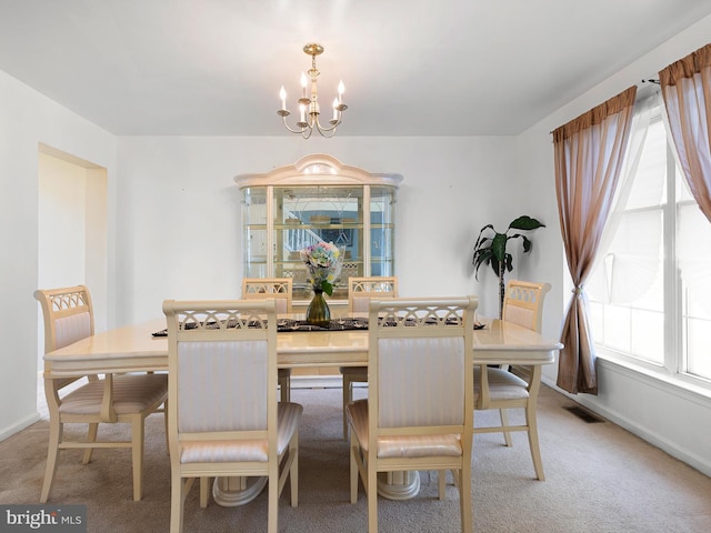 carpeted dining room featuring visible vents, baseboards, a notable chandelier, and a healthy amount of sunlight