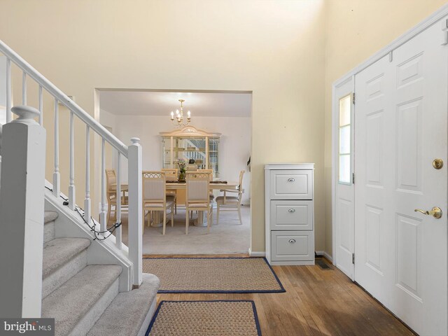 foyer entrance featuring a chandelier, a wealth of natural light, wood finished floors, and stairway