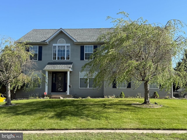colonial-style house with a shingled roof and a front yard