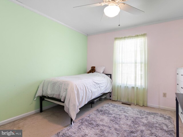 carpeted bedroom with visible vents, ornamental molding, baseboards, and a ceiling fan