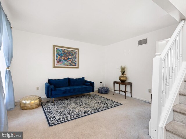 carpeted living room featuring baseboards, stairs, and visible vents