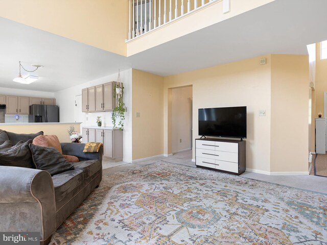 living area featuring baseboards, light carpet, and a towering ceiling