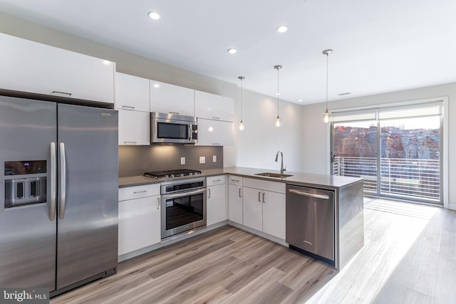 1350 Maryland Ave NE Unit 116, Washington, DC 20002 - kitchen with white cabinets, hanging light fixtures, appliances with stainless steel finishes, a sink, and light wood finished floors