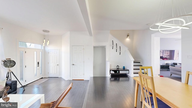 foyer featuring stairs, a chandelier, and dark wood-style floors