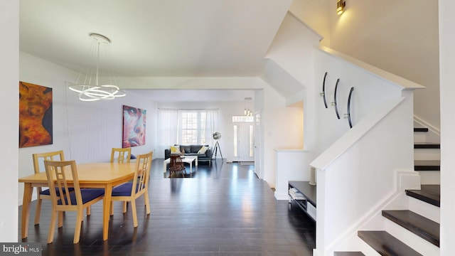 dining room with an inviting chandelier, stairway, and dark wood-type flooring