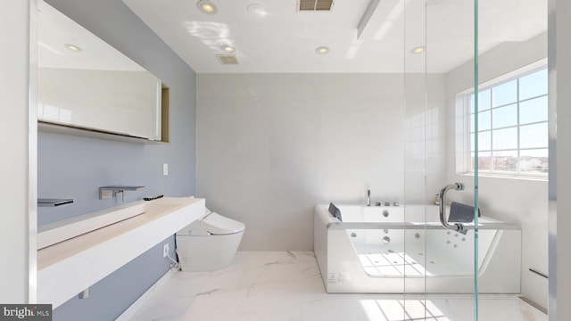bathroom with a tub with jets, vanity, toilet, marble finish floor, and recessed lighting