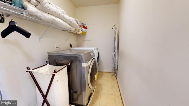 clothes washing area with laundry area, washer and clothes dryer, and light tile patterned floors