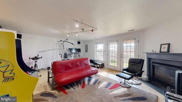living room with a glass covered fireplace, french doors, and visible vents