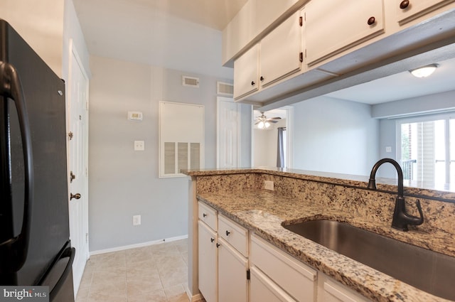 kitchen with ceiling fan, visible vents, light stone countertops, a sink, and freestanding refrigerator