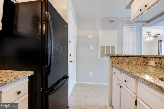 kitchen with white cabinets, light stone countertops, ceiling fan, freestanding refrigerator, and visible vents