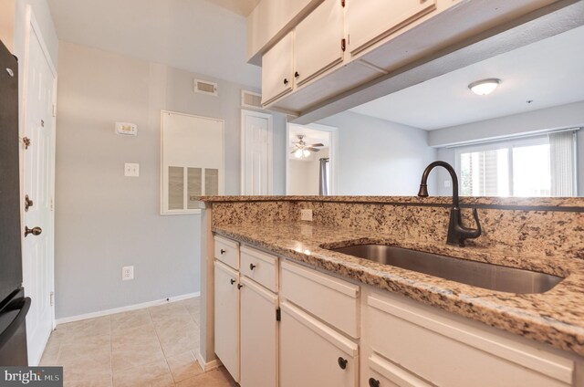 kitchen with a sink, light stone counters, and visible vents