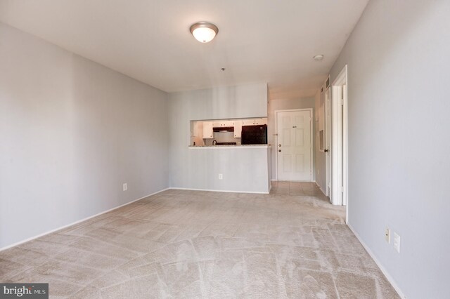 unfurnished room featuring light colored carpet and baseboards