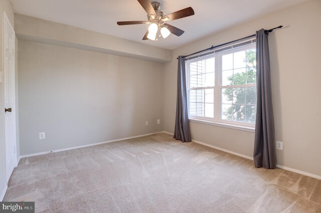 carpeted empty room featuring baseboards, plenty of natural light, and a ceiling fan