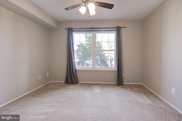 carpeted spare room with ceiling fan and baseboards