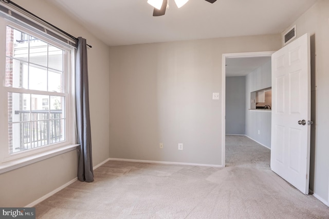 empty room featuring light colored carpet, baseboards, and ceiling fan