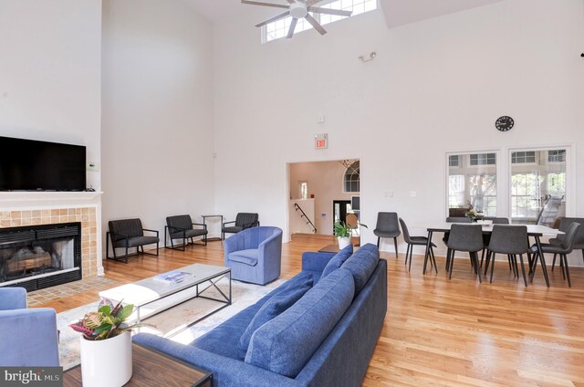 living room featuring a ceiling fan, high vaulted ceiling, plenty of natural light, and light wood-type flooring