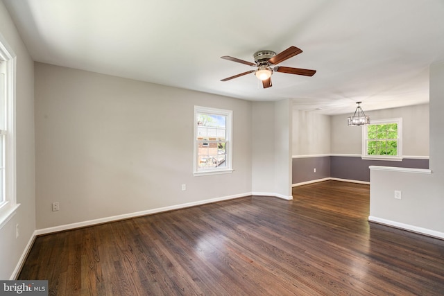 empty room with baseboards, ceiling fan with notable chandelier, and wood finished floors