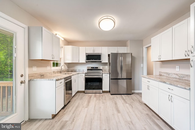 kitchen featuring a sink, white cabinets, stainless steel appliances, and light wood-type flooring
