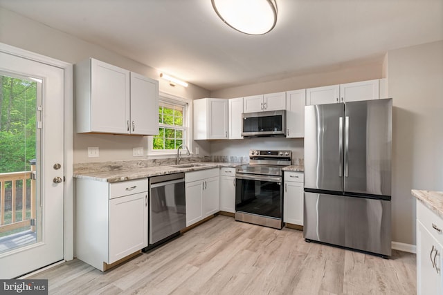 kitchen featuring light wood-style floors, white cabinets, stainless steel appliances, and a sink