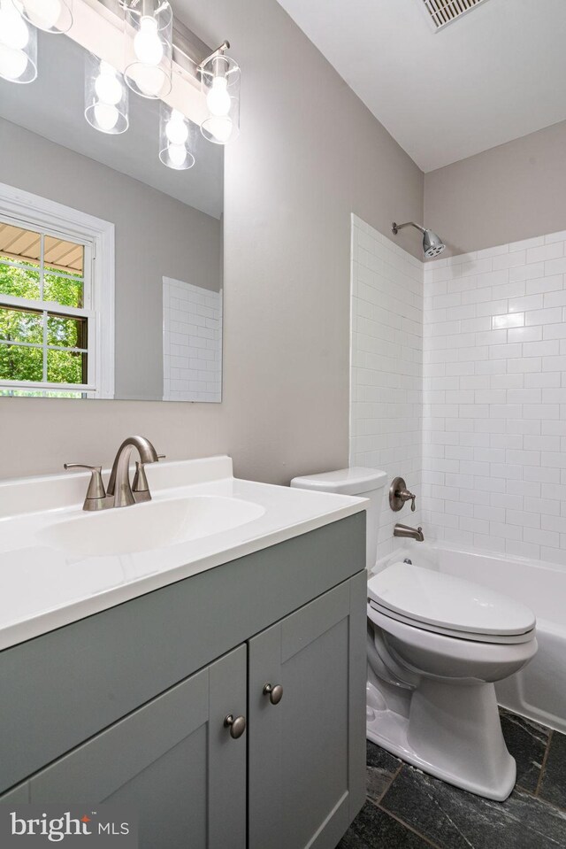 full bath with vanity, toilet, stone finish floor, bathing tub / shower combination, and visible vents
