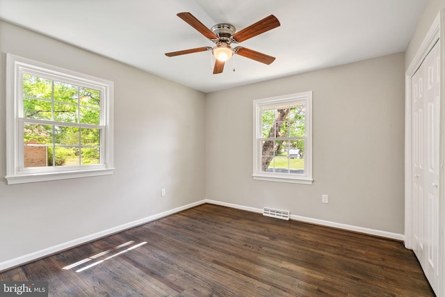 unfurnished bedroom with visible vents, baseboards, dark wood-style floors, and a closet