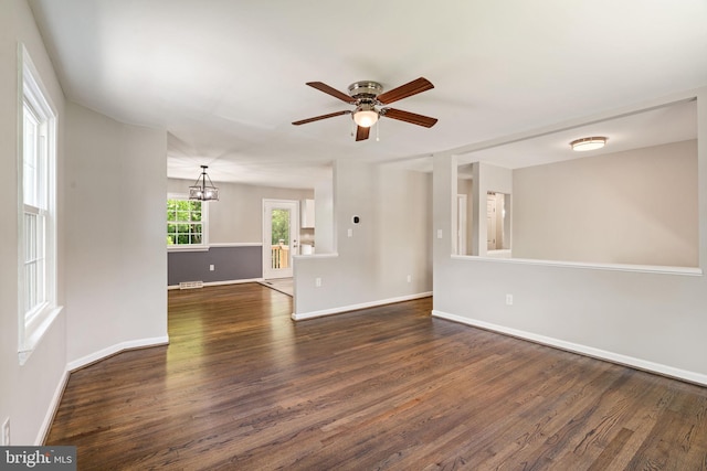 unfurnished room with baseboards, dark wood finished floors, and ceiling fan with notable chandelier