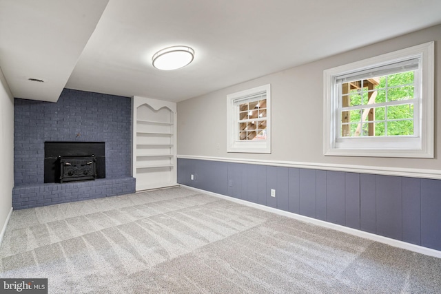 unfurnished living room featuring carpet flooring and a wainscoted wall