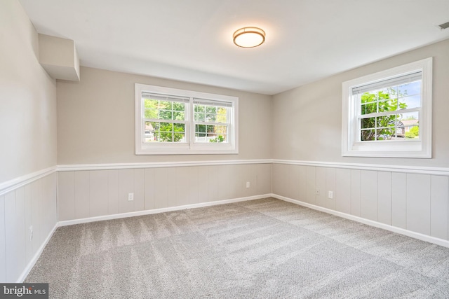 carpeted spare room with visible vents and wainscoting