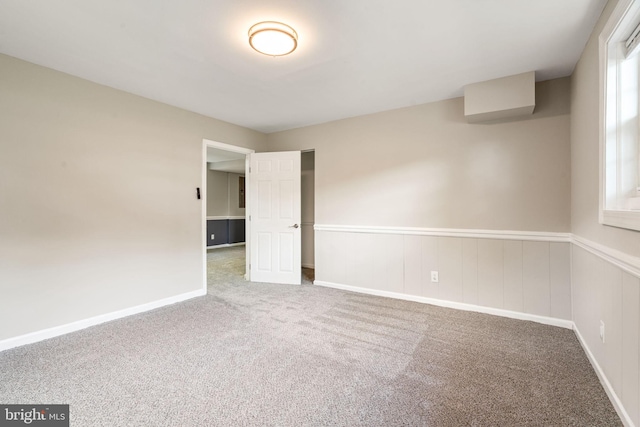 empty room with carpet floors and wainscoting
