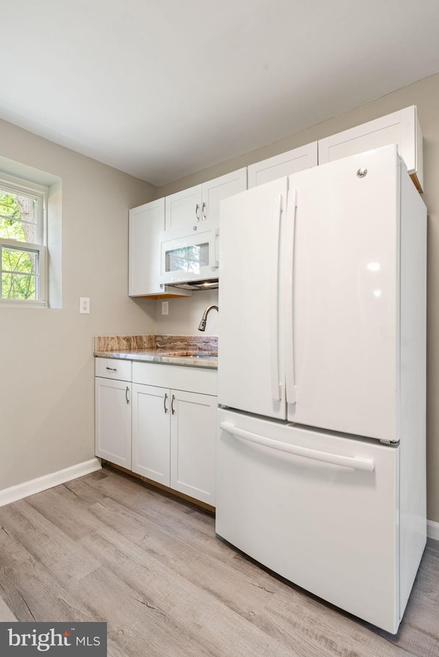 kitchen featuring light wood-type flooring, a sink, white cabinets, and white appliances