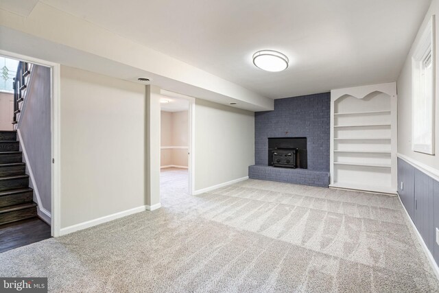 unfurnished living room featuring a wood stove, carpet floors, a wealth of natural light, and stairway